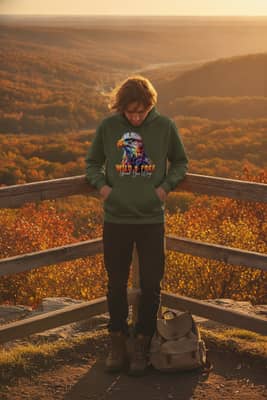 Person in a military green hoodie leans on a wooden railing overlooking a valley during a golden hour hike.
