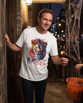 A person in a white lion t-shirt stands at an open apartment door handing candy to an unseen trick-or-treater.
