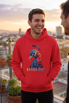 A person wearing a deep red hoodie laughs with a friend on a city rooftop under warm golden hour sunlight.